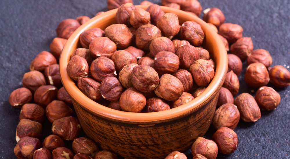 Macro shot of hazelnuts in bowl . On stone background